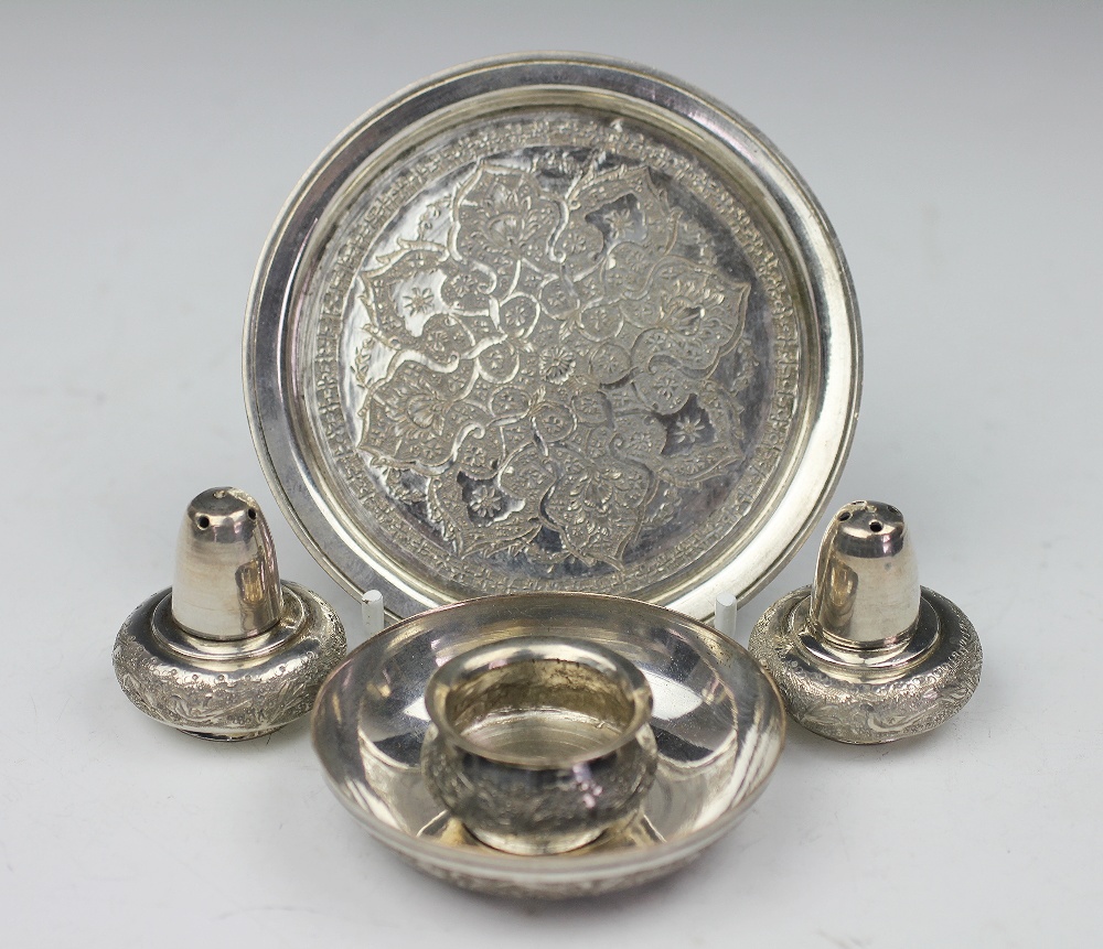 A Persian white metal condiment set, comprising a circular tray, two pepperettes and a salt,