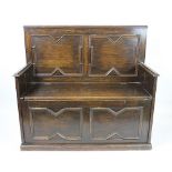 A 1920's century box seat settle, the panelled back above a hinged seat, on plinth base, 95.