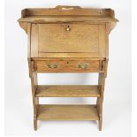 An Arts & Crafts oak students desk, with fall above a drawer, on standard end supports,