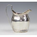 A George III silver milk jug, London 1799, of oval form and with chased laurel wreath decoration,