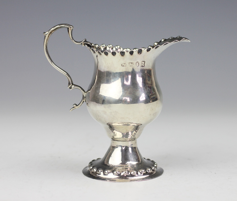 A George III silver pedestal milk jug 'WC' London 1774, of pedestal form and with crimped rim,