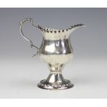 A George III silver pedestal milk jug 'WC' London 1774, of pedestal form and with crimped rim,