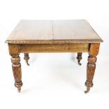 An Edwardian oak extending dining table, with egg and dart carved edge, on turned and fluted legs,