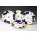 Four Coalport batwing dinner plates, each gilt and florally decorated against a cobalt ground,