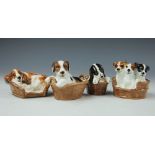 A collection of four Royal Doulton puppies in baskets, to include; HN2588, HN2587,