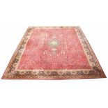 A large red ground carpet, decorated all-over with a stylised tree of life design,