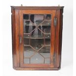 A George III mahogany hanging corner cabinet, with astragal glazed door enclosing shelves,