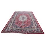 A Kashmir rug, worked with an ivory medallion and all over foliate design against a red ground,