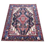 A Caucasian wool rug, worked with a foliate medallion design against a deep blue ground,