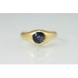 A sapphire set ring, the circular stone within rub-over setting,