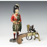 A table tinder lighter with flintlock pistol mechanism and candlestick sconce to the side,