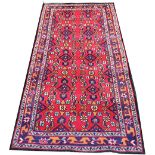 A Caucasian wool runner, worked with a foliate design against a red ground,