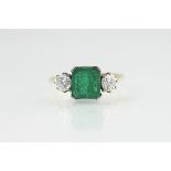 An emerald and diamond three stone ring, the central square,