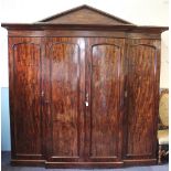 A William IV mahogany break front wardrobe, of architectural form, with arched pediment,