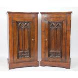 A pair of carved oak pier type cabinets, 19th century and later, with Gothic carved panelled doors,