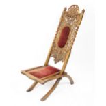 A late Victorian carved oak folding coaching chair, carved with leaves,