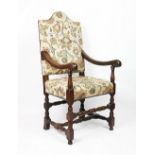 A 17th century style carved oak chair, with floral upholstery and scroll end arms,