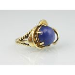 A synthetic star sapphire set ring, the circular cabochon stone within six claw setting,