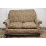 A Victorian two seater settee, florally upholstered with two cushions and spring base,