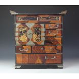 A Japanese parquetry table top cabinet, with an arrangement of drawers and doors,