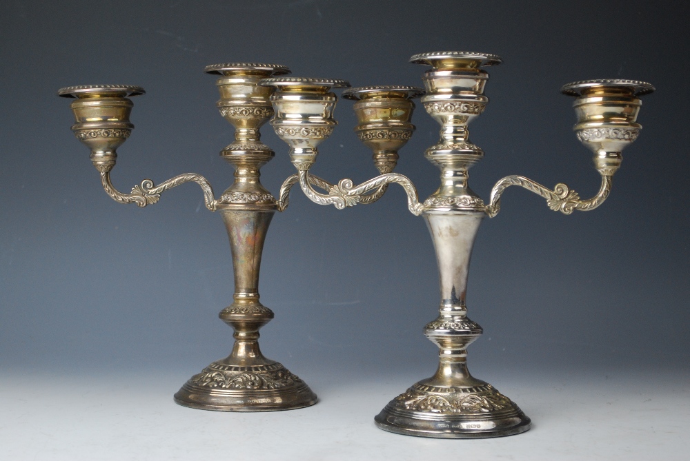 A pair of silver candelabra, W I Broadway & Co, Birmingham 1978, each embossed with floral sprays,