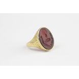 An intaglio set signet ring, the carnelian carved oval seal depicting peacock crest and motto,