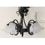A wrought iron five light chandelier, with frosted glass shades,