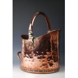 A 19th century rivet bound copper coal scuttle, with planished detailing and swivel handle,