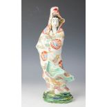 A Japanese porcelain figure of a Geisha, modelled wearing a robe decorated with bianco-sopra-bianco,