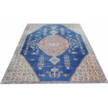 A Caucasian wool carpet, worked with an all over foliate design, against a blue ground,
