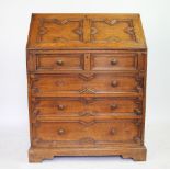 A carved oak bureau, with fielded fall above two short and three long drawers on bracket feet,