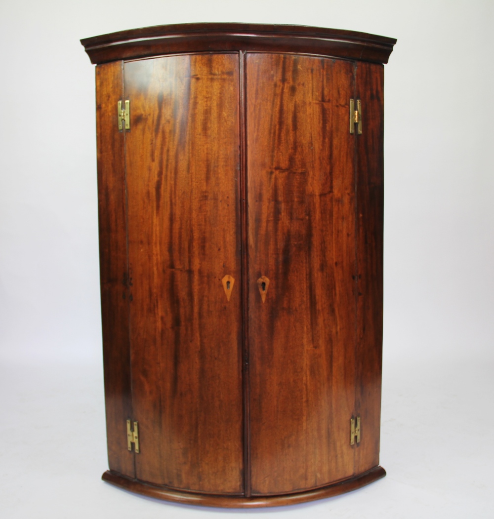 A George III mahogany bow front corner cabinet,