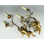 A pair of gilt wood and gilt metal figural twin branch wall lights, modelled with cherubs,