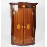 A George III inlaid mahogany bow front corner cabinet, with shell patera,