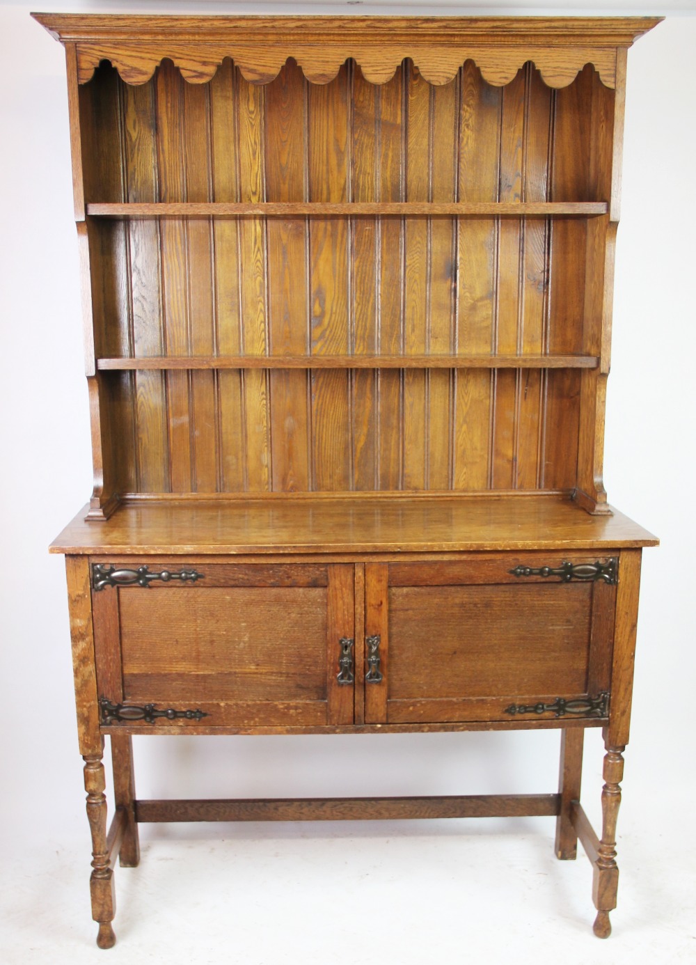 An Edwardian oak dresser, with plate rack above two cupboard doors, on turned legs,