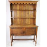 An Edwardian oak dresser, with plate rack above two cupboard doors, on turned legs,