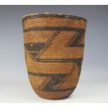 A Native American basket, decorated with a coiled monochrome geometric design, 26cm high.