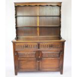A 1920's oak dresser, with open shelves above two drawers and two cupboard doors, on stile feet,
