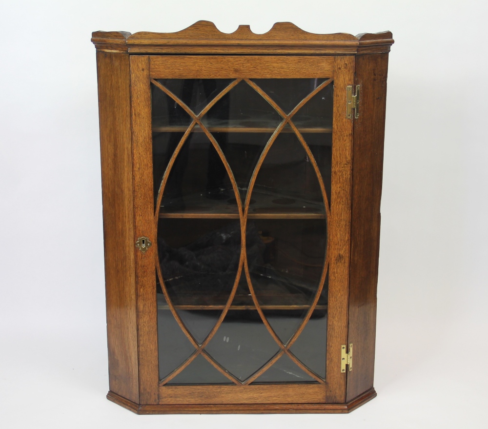 A George III oak hanging corner cabinet, with astragal glazed door,