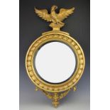 A Regency gilt wood and gesso convex wall mirror, with eagle mount,