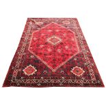 A Qashquai tribal wool carpet, worked with a central large lozenge against a red ground,