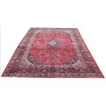 A Persian Qashquai wool carpet, worked with an all over foliate design against a red ground,
