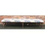 A Victorian oak window seat of long proportions, with upholstered seat, on six turned legs,