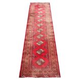 An Iranian wool runner, worked with a Bokhara design against a red ground,