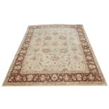 A hand woven Ziegler wool carpet, worked with an all over bold floral design against a beige ground,