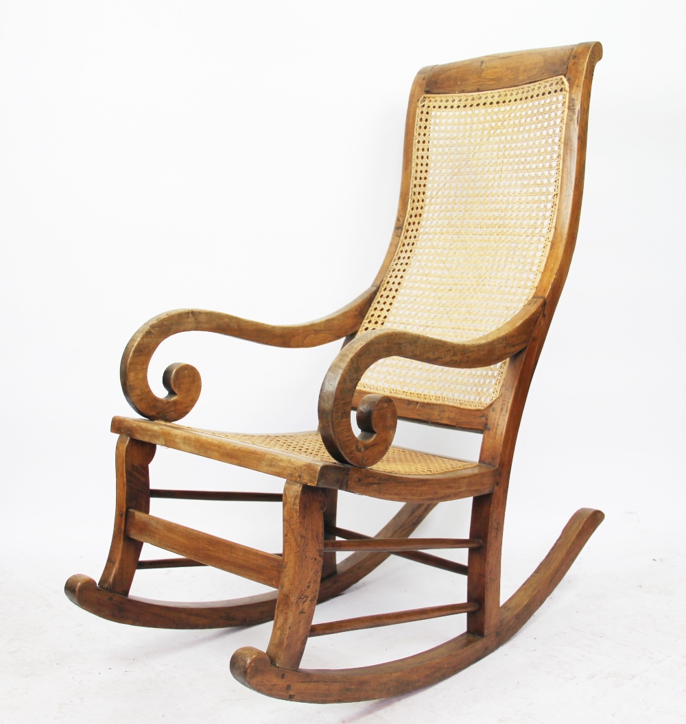 A Victorian ash rocking chair, with caned back and seat,