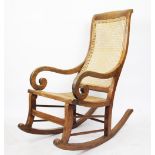 A Victorian ash rocking chair, with caned back and seat,
