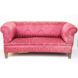 A Victorian drop end settee, with red floral upholstery, on oak tapered legs,