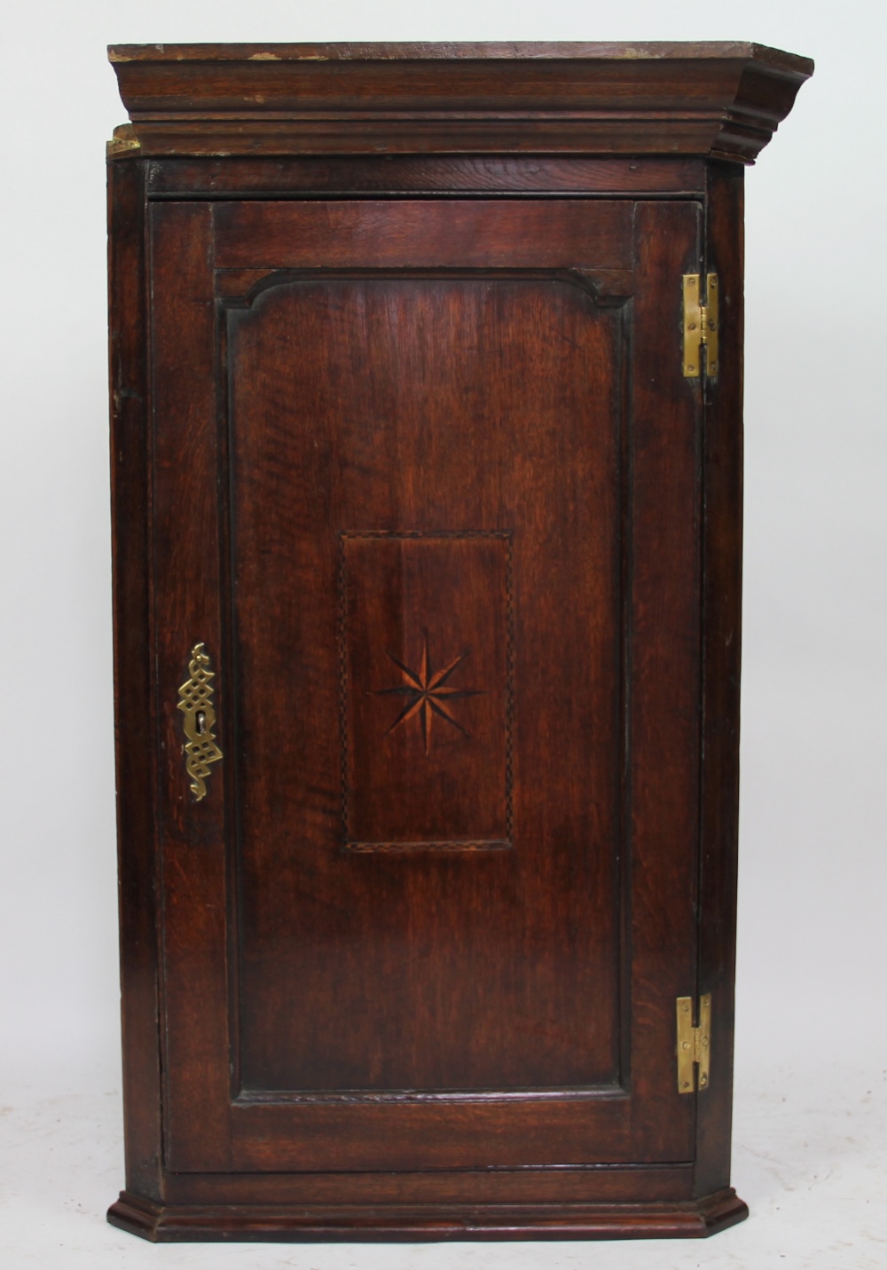 A George III oak hanging corner cabinet, with star inlaid door,