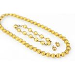 A yellow metal bead necklace with matching earrings and bracelet en suite,